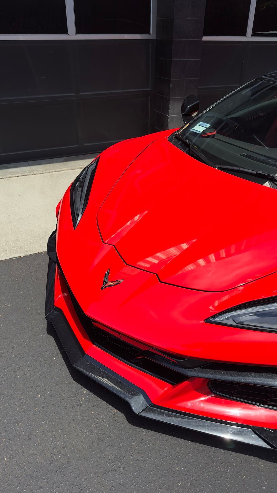 Red sports car front end in a showroom, with glossy paint and black accents.