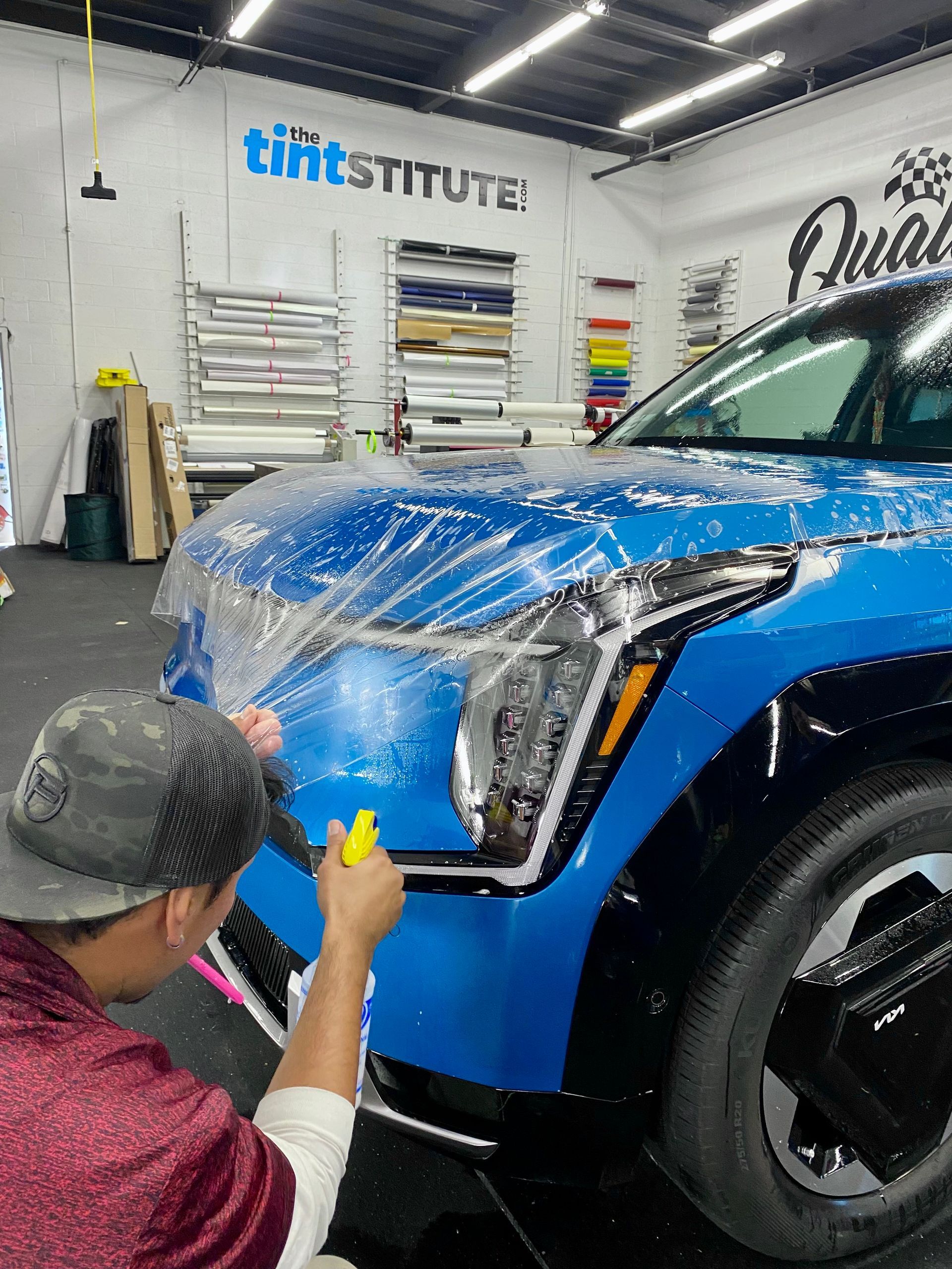 Detailing a blue SUV with paint protection film in an auto shop