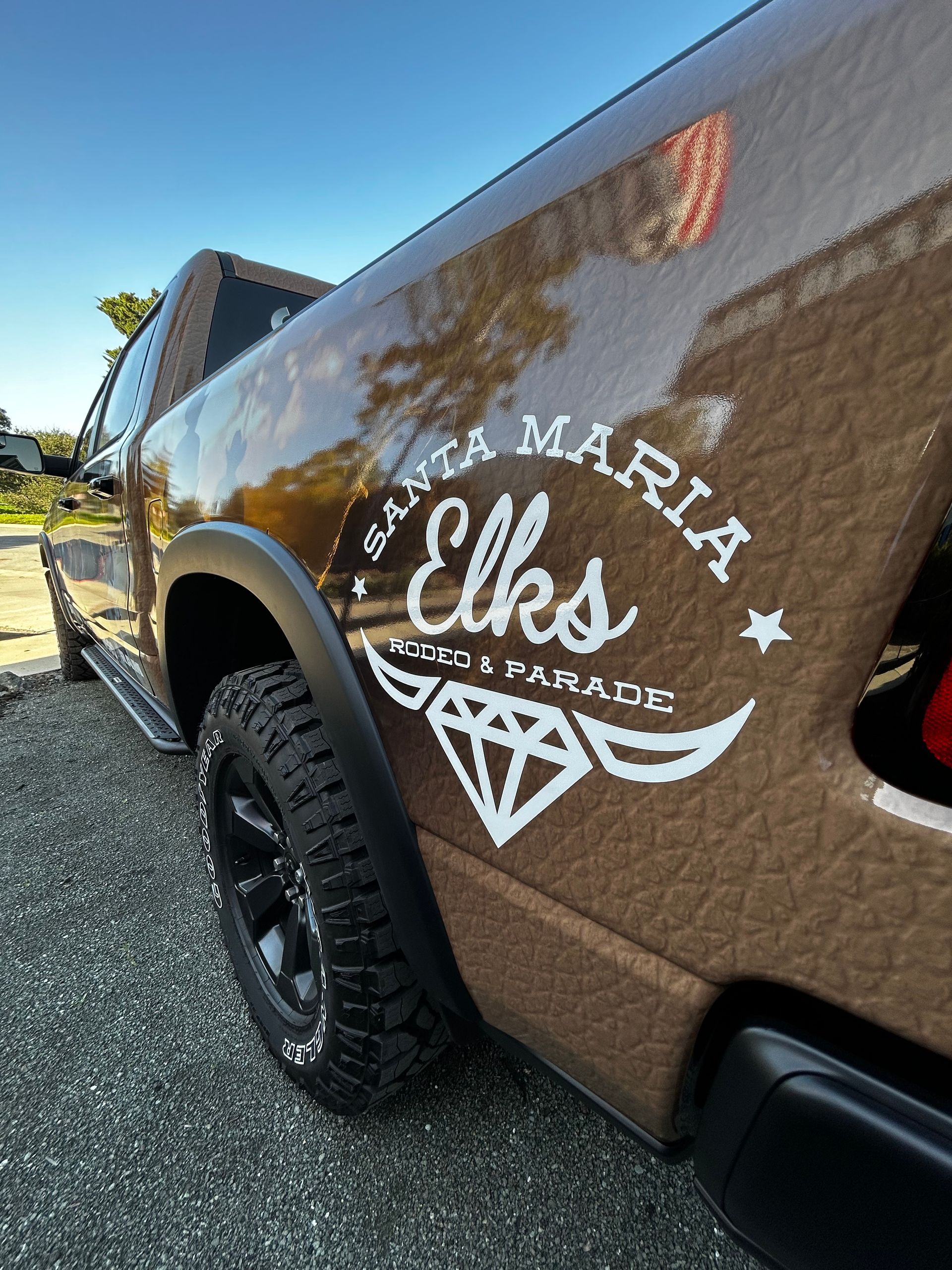 Brown truck side with white “St. Maria Elks” logo and diamond graphic outdoors.