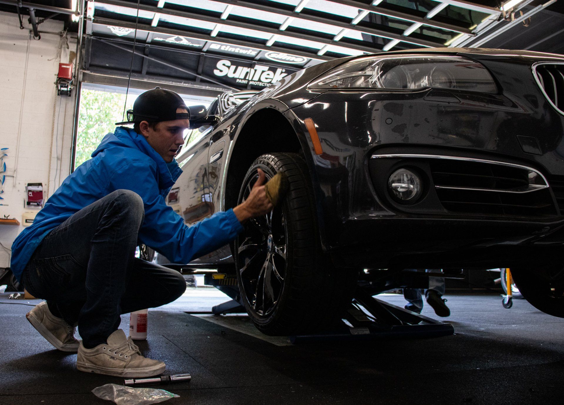 Mechanic cleaning a black car’s wheel in a garage