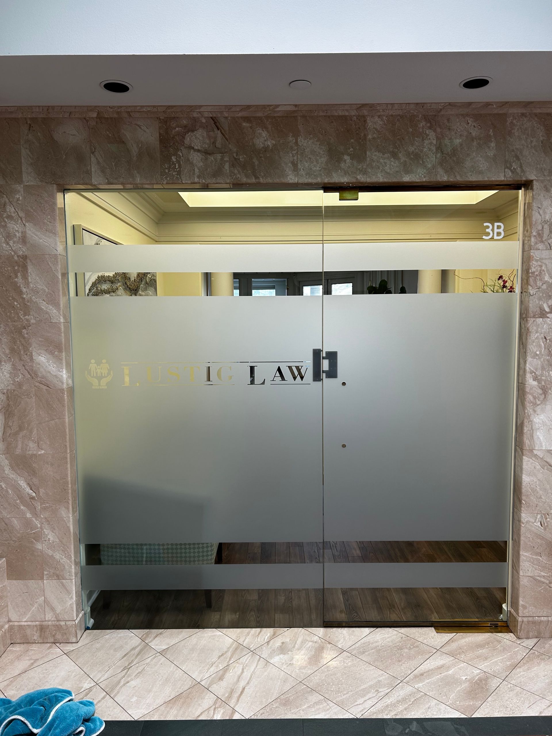 Frosted glass double doors with gold trim in a marble lobby.