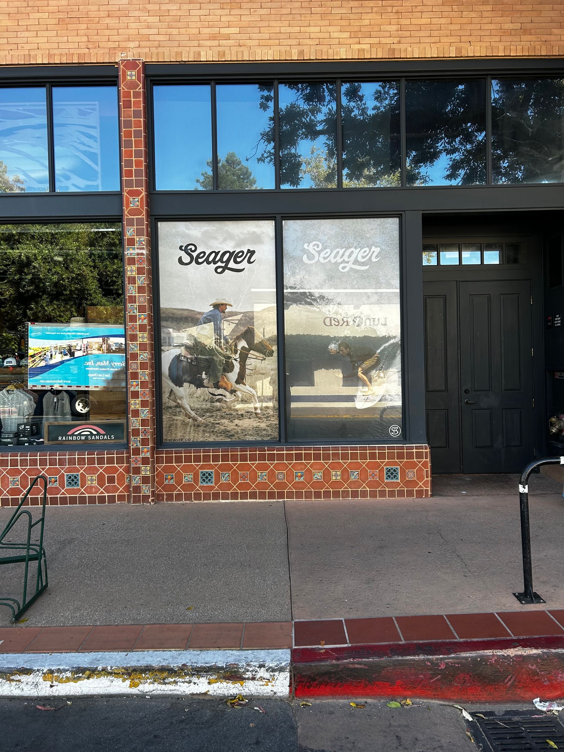 Storefront with large window posters and a dark entrance door on a brick facade.