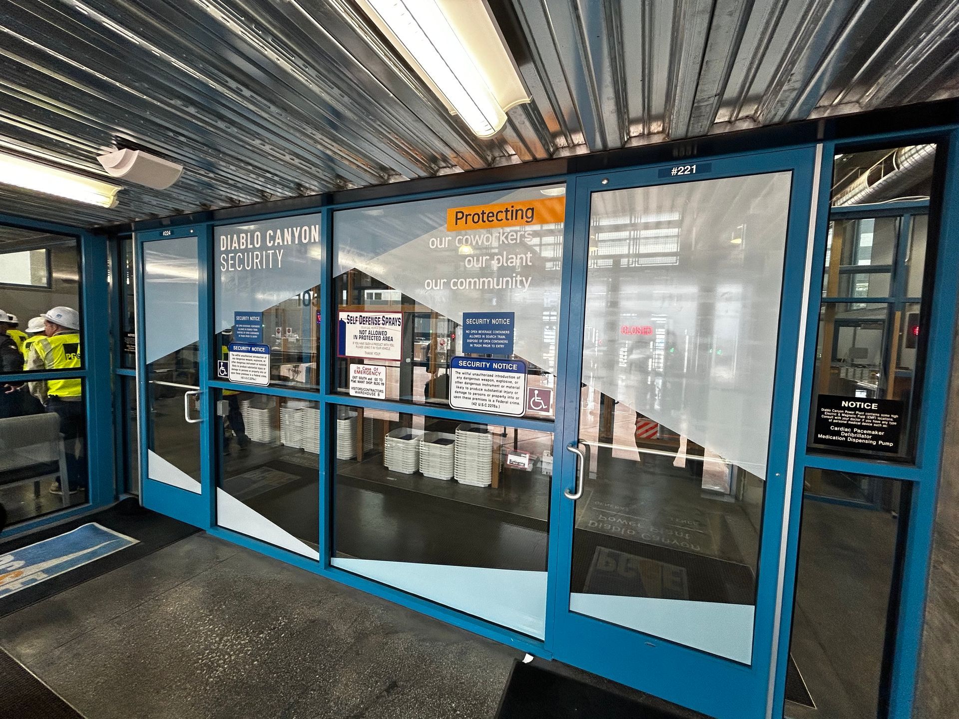 Blue-framed glass entrance doors to a storefront under a corrugated metal awning