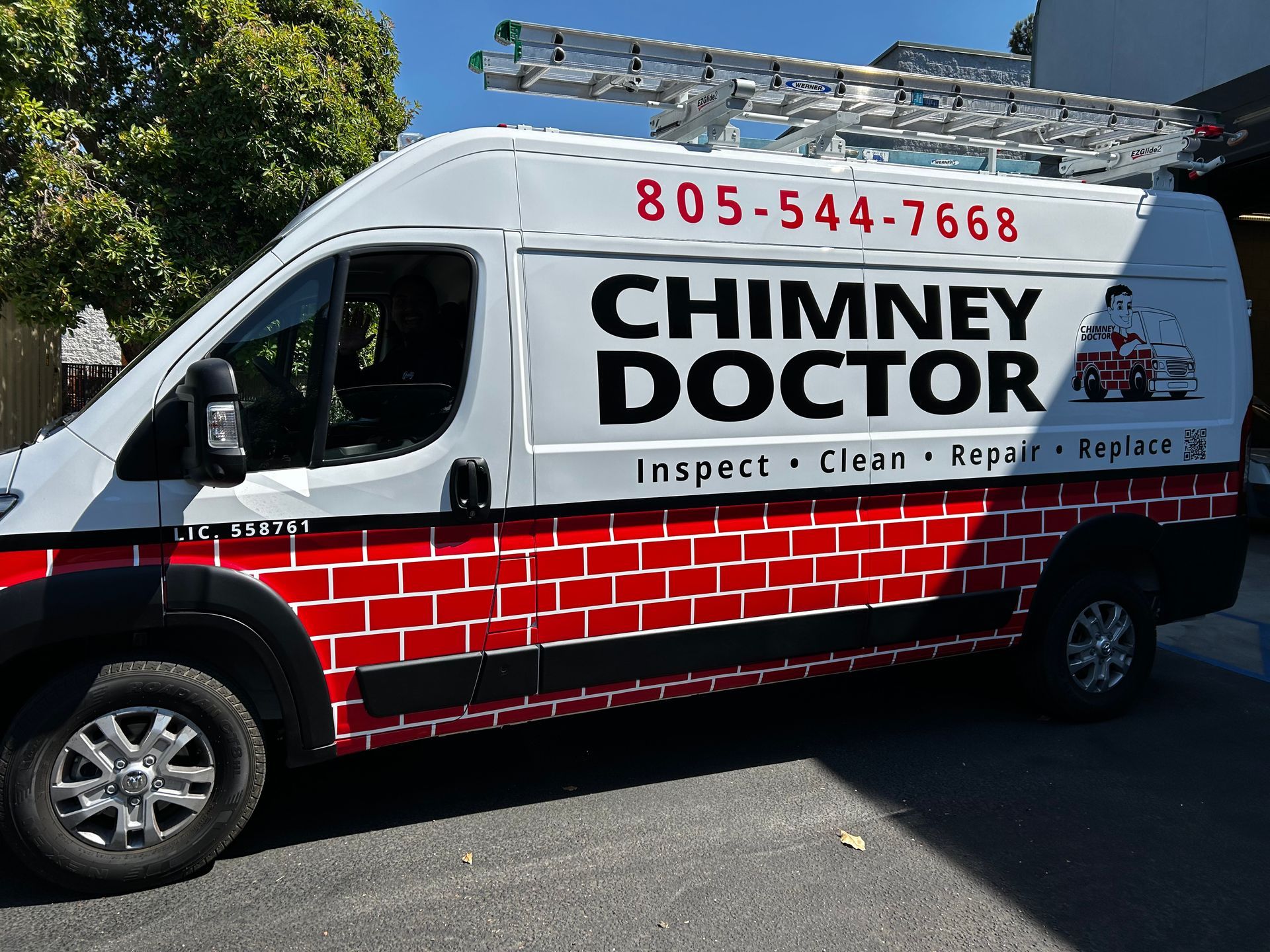 White Chimney Doctor service van with red brick graphic and ladder on top parked on a street