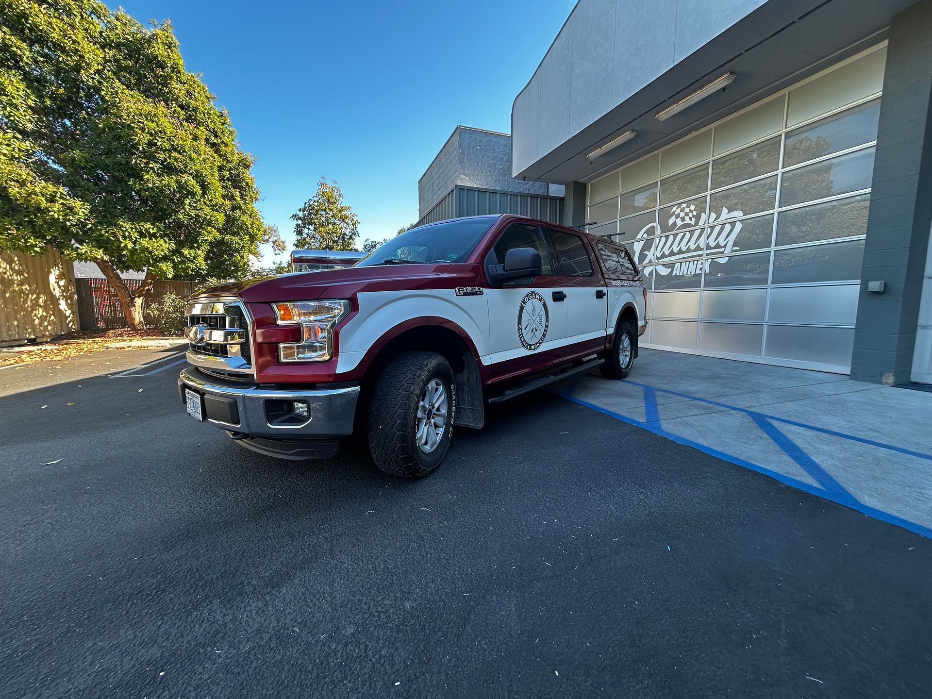 Red pickup truck parked outside a modern building with blue handicap markings on the pavement