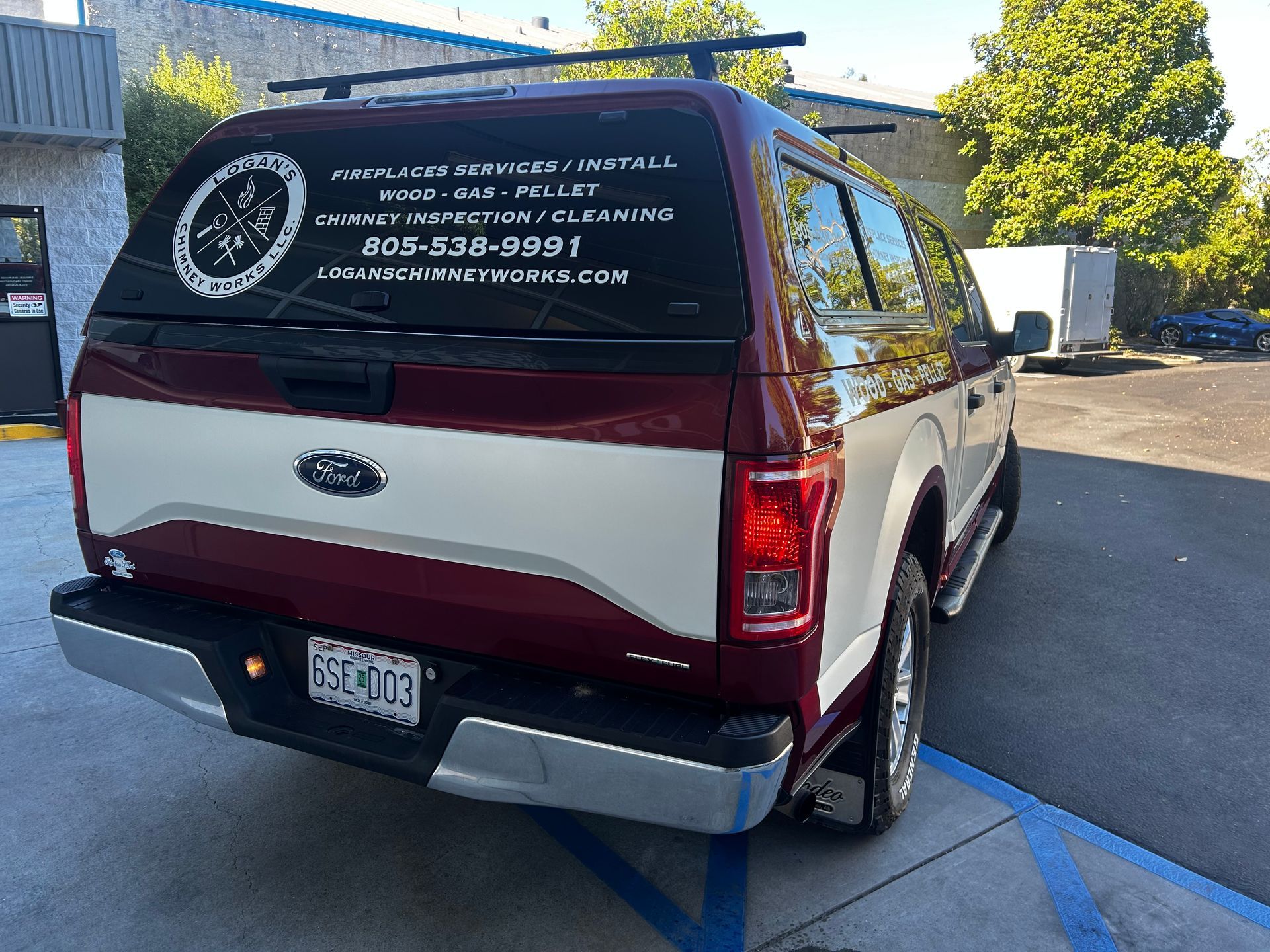 Maroon-and-white SUV with company branding parked in a lot on a sunny day