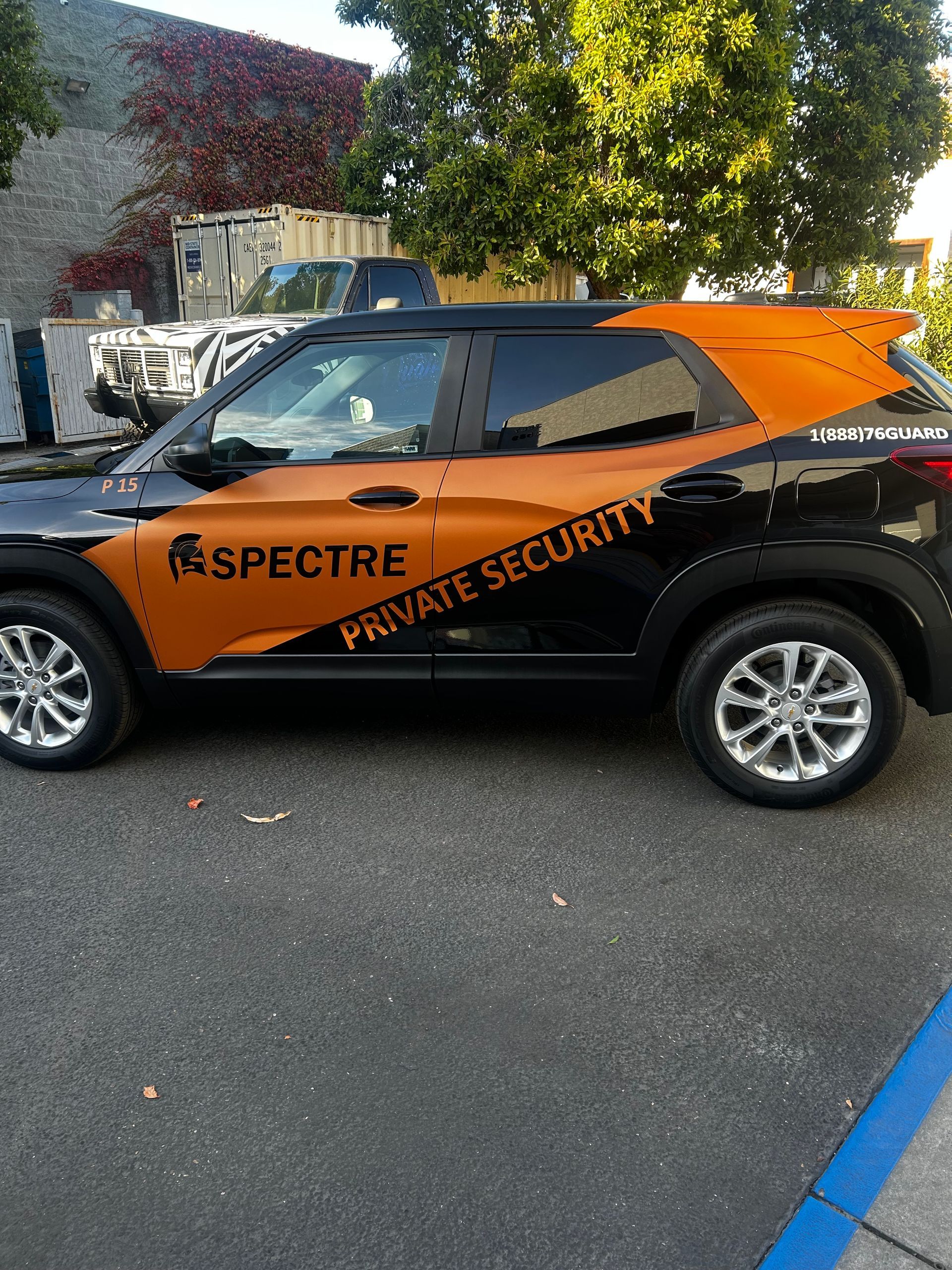 Orange-and-black Spectre private security SUV parked on a street near a building