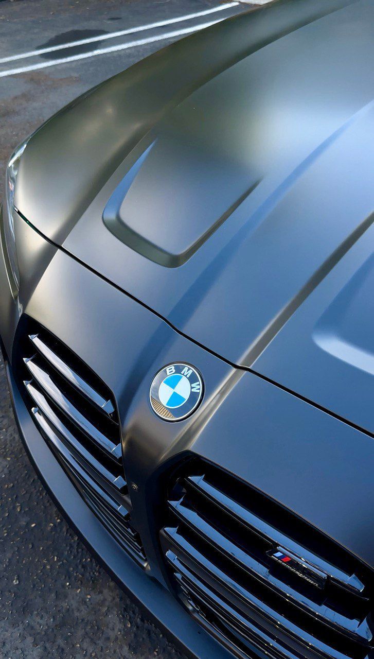 Close-up of a blue BMW car hood and grille parked outdoors