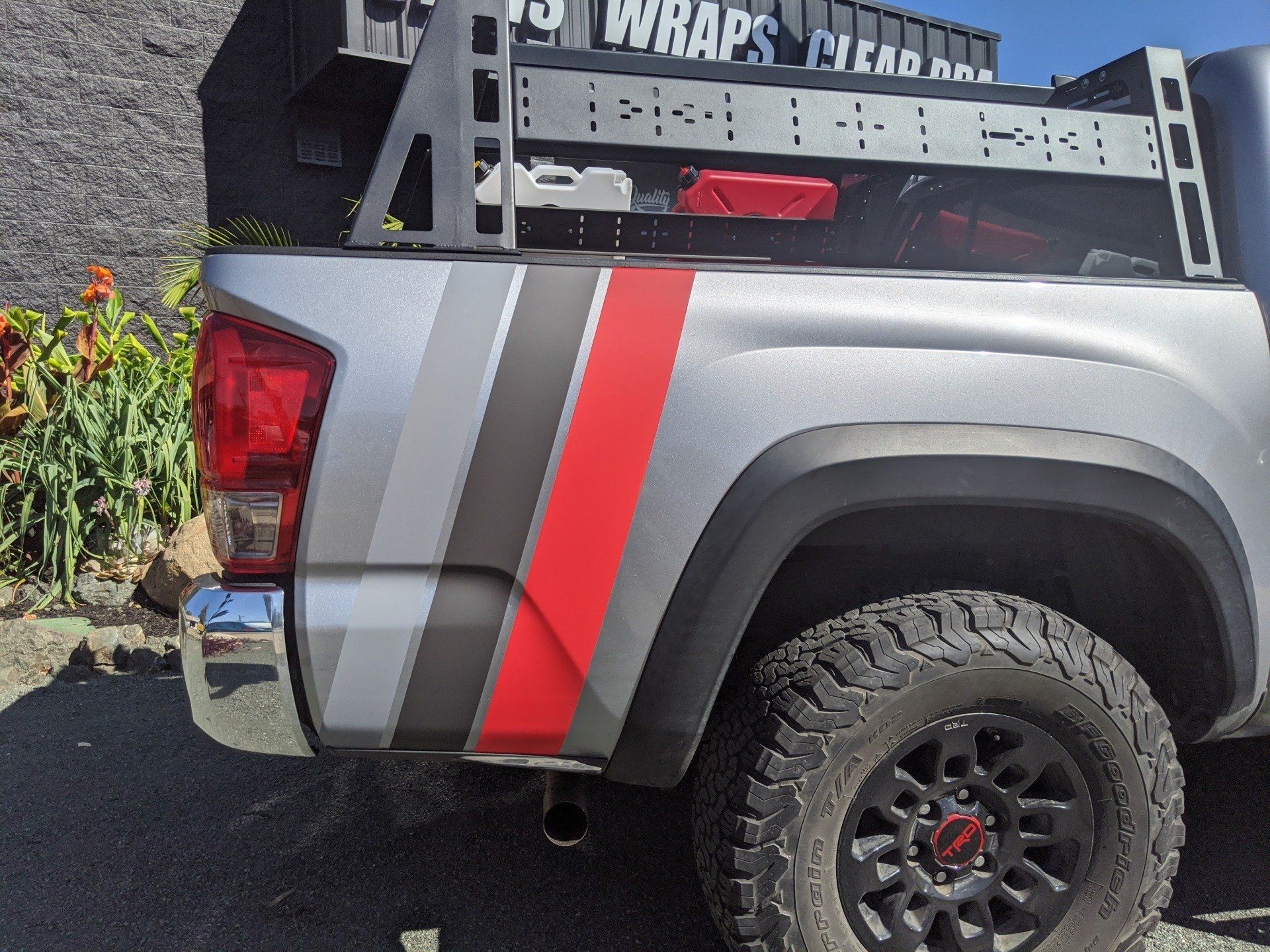Silver pickup truck with red racing stripe and black off-road wheels, parked outdoors.