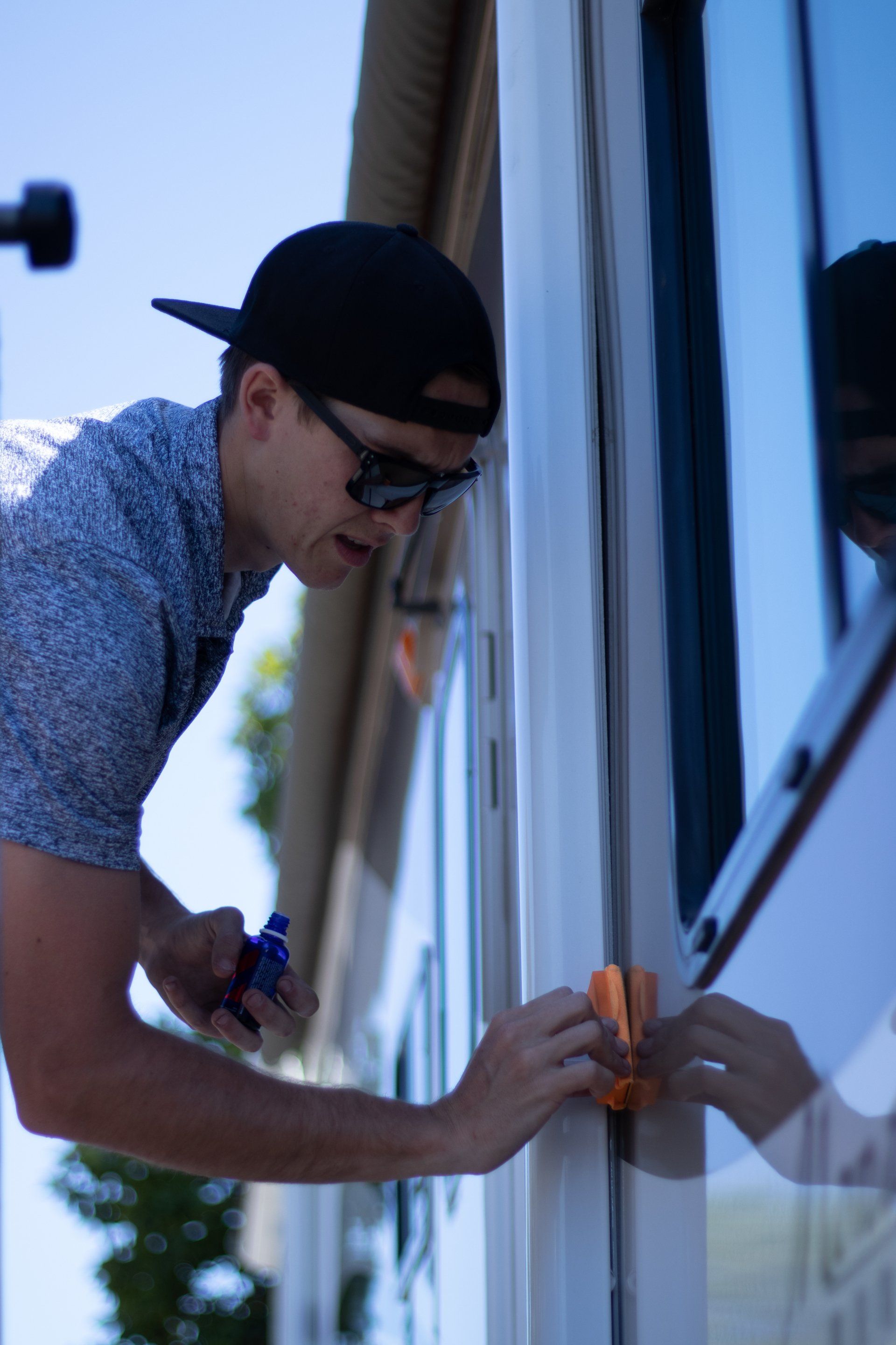 Man in a cap cleaning a window on the side of a house