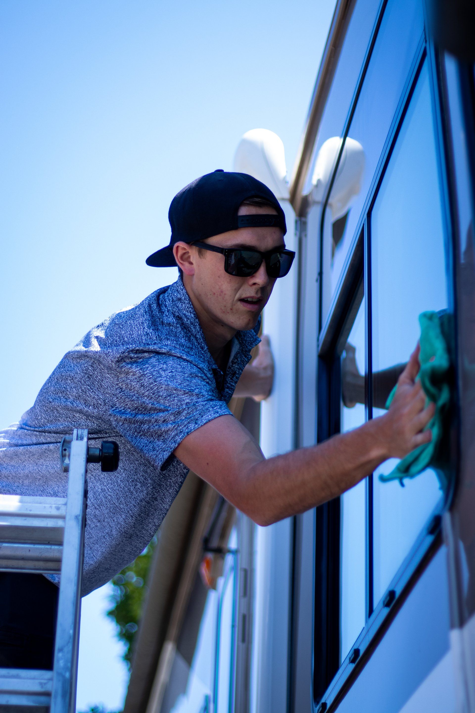 Man cleaning a blue window with a squeegee on the side of a building