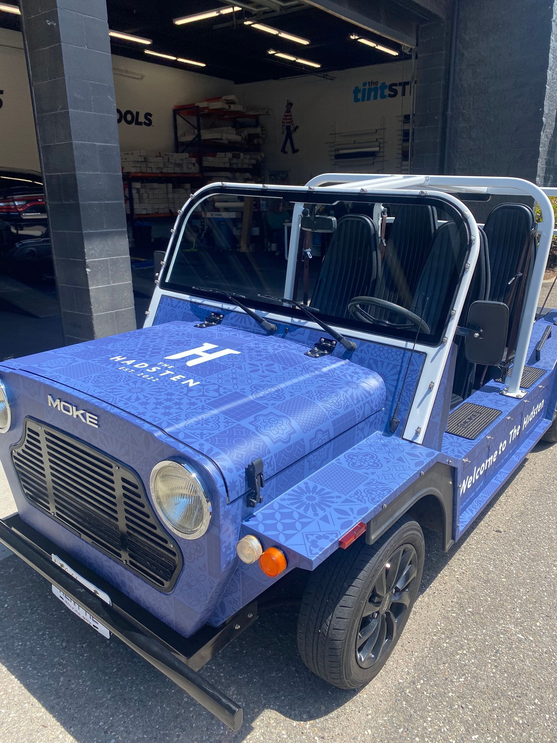 Blue vintage off-road jeep with white roll bar parked in a garage