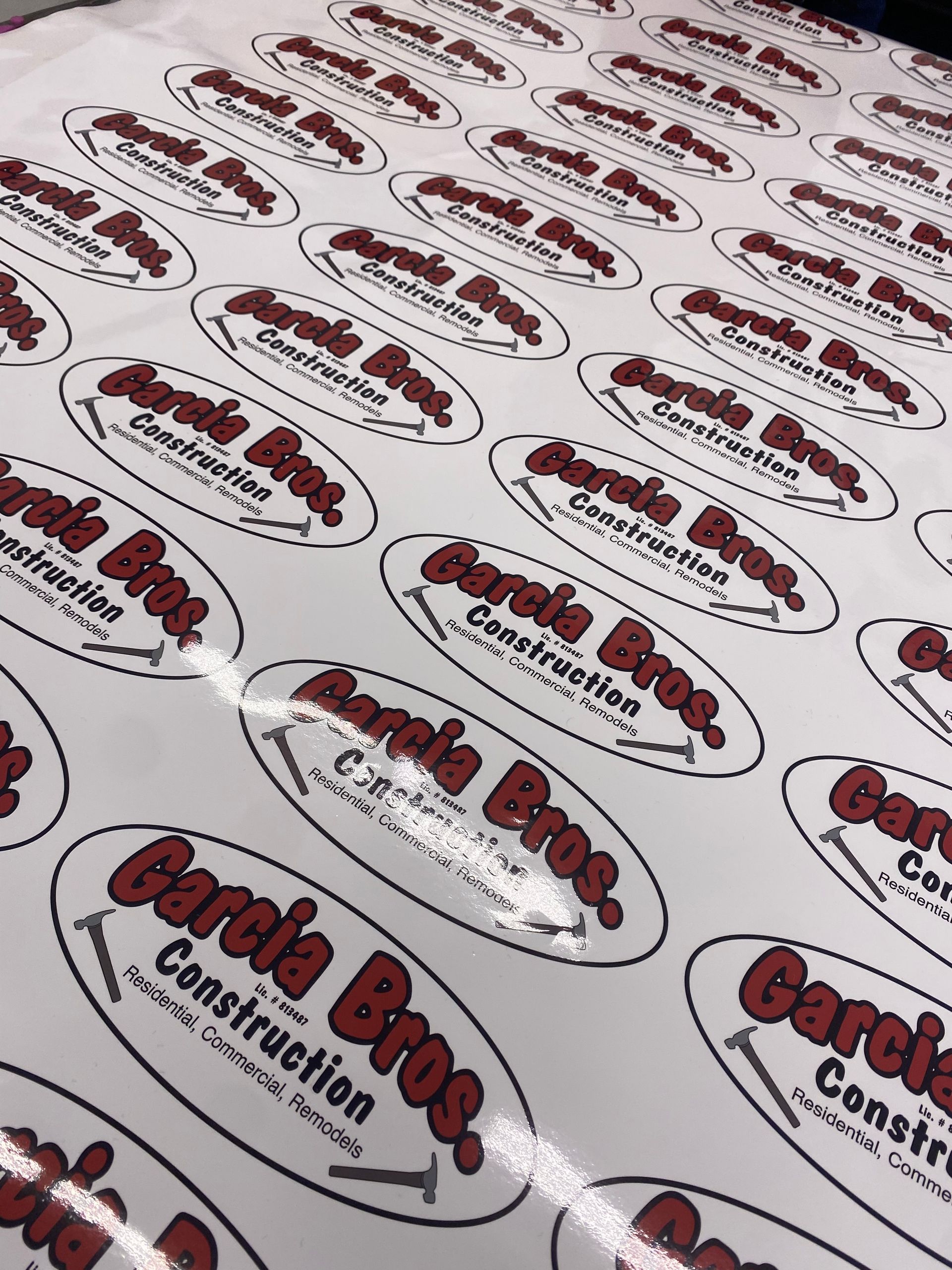 Sheets of white stickers printed with the red and black “Garcia Bros Construction” logo.