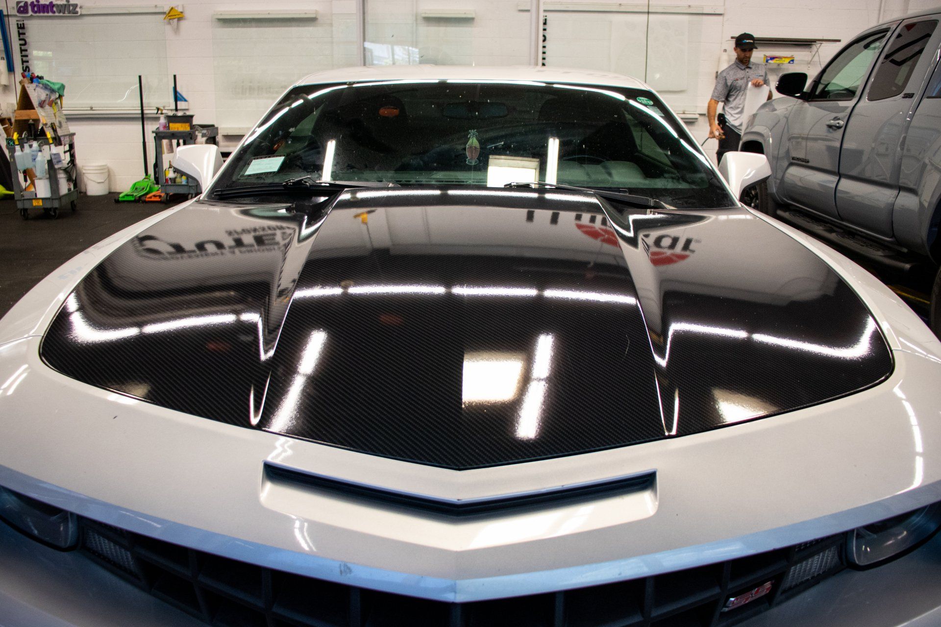 Black sports car with white hood accents in a garage, front view