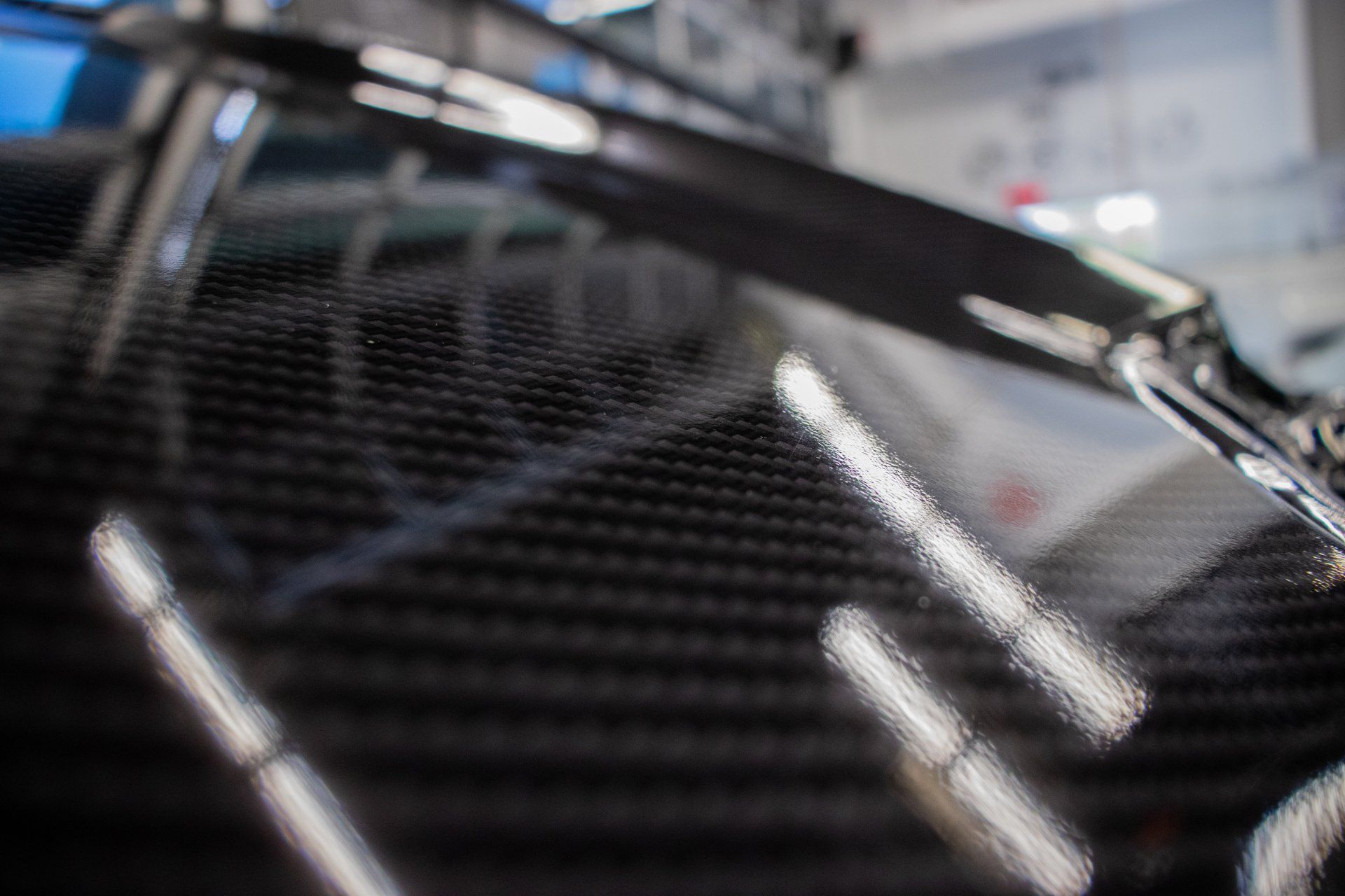 Close-up of a glossy black carbon fiber surface with reflective light streaks