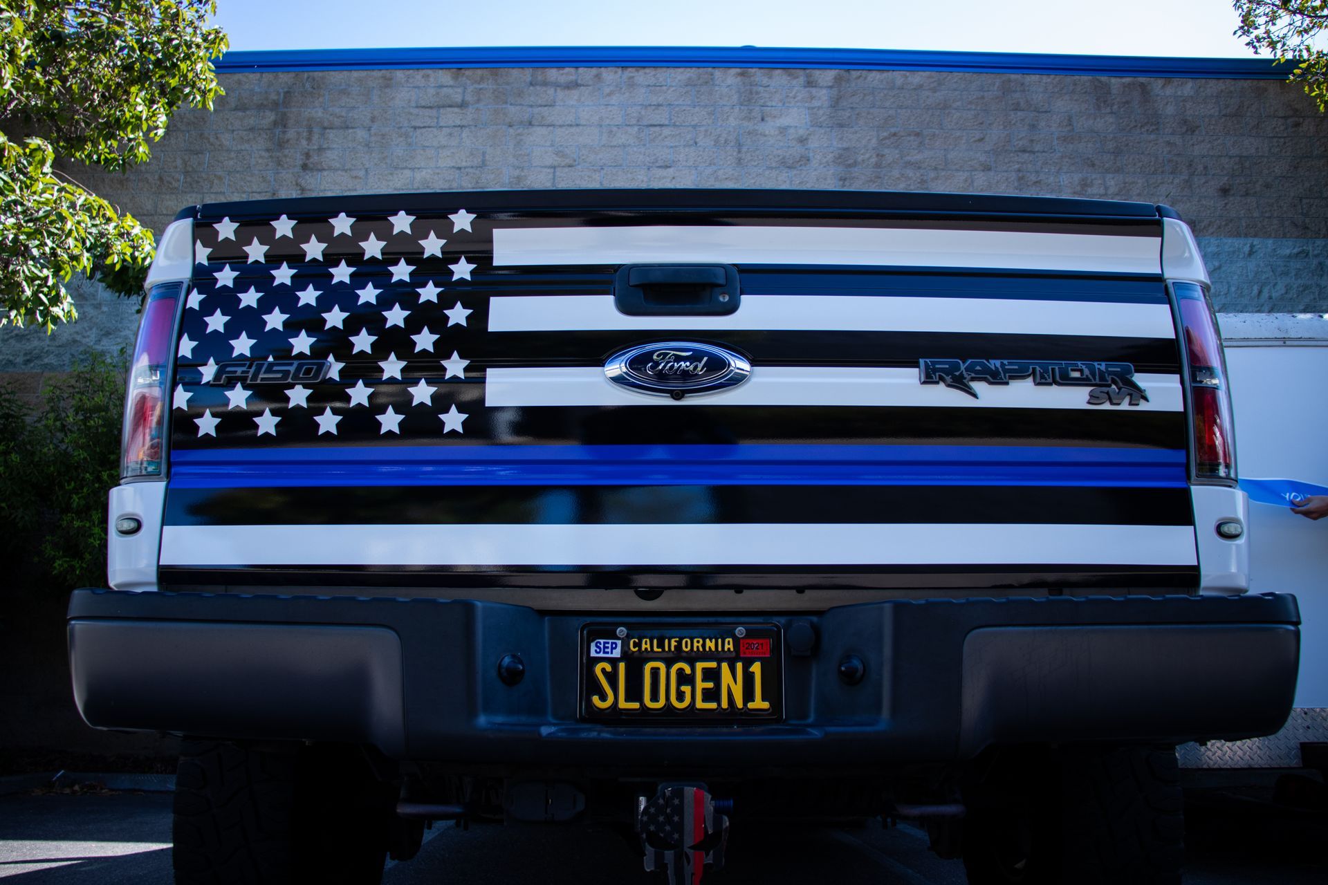 Ford pickup tailgate with black-and-white American flag design and a custom license plate.