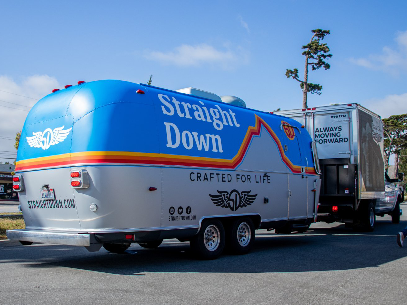 Blue Straight Down trailer hitched to a truck in a parking lot under a clear sky