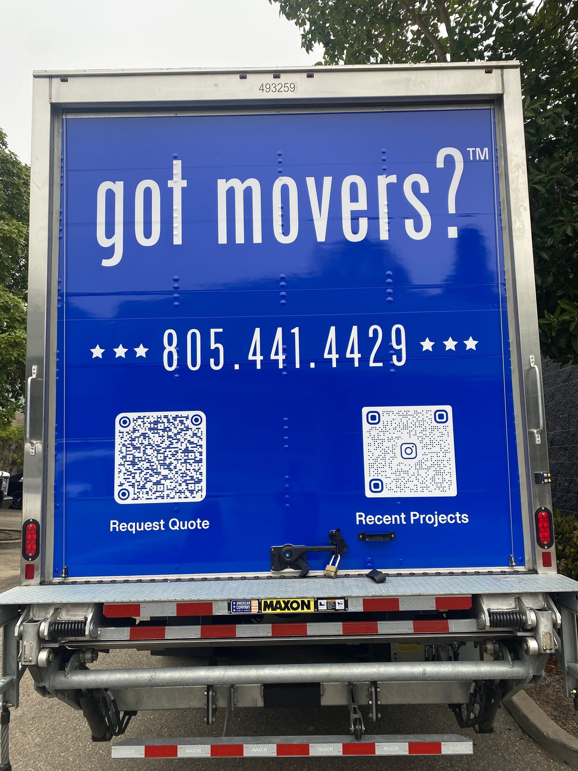 Blue moving-truck ad reading “got movers?” with phone number and QR codes on the back door.