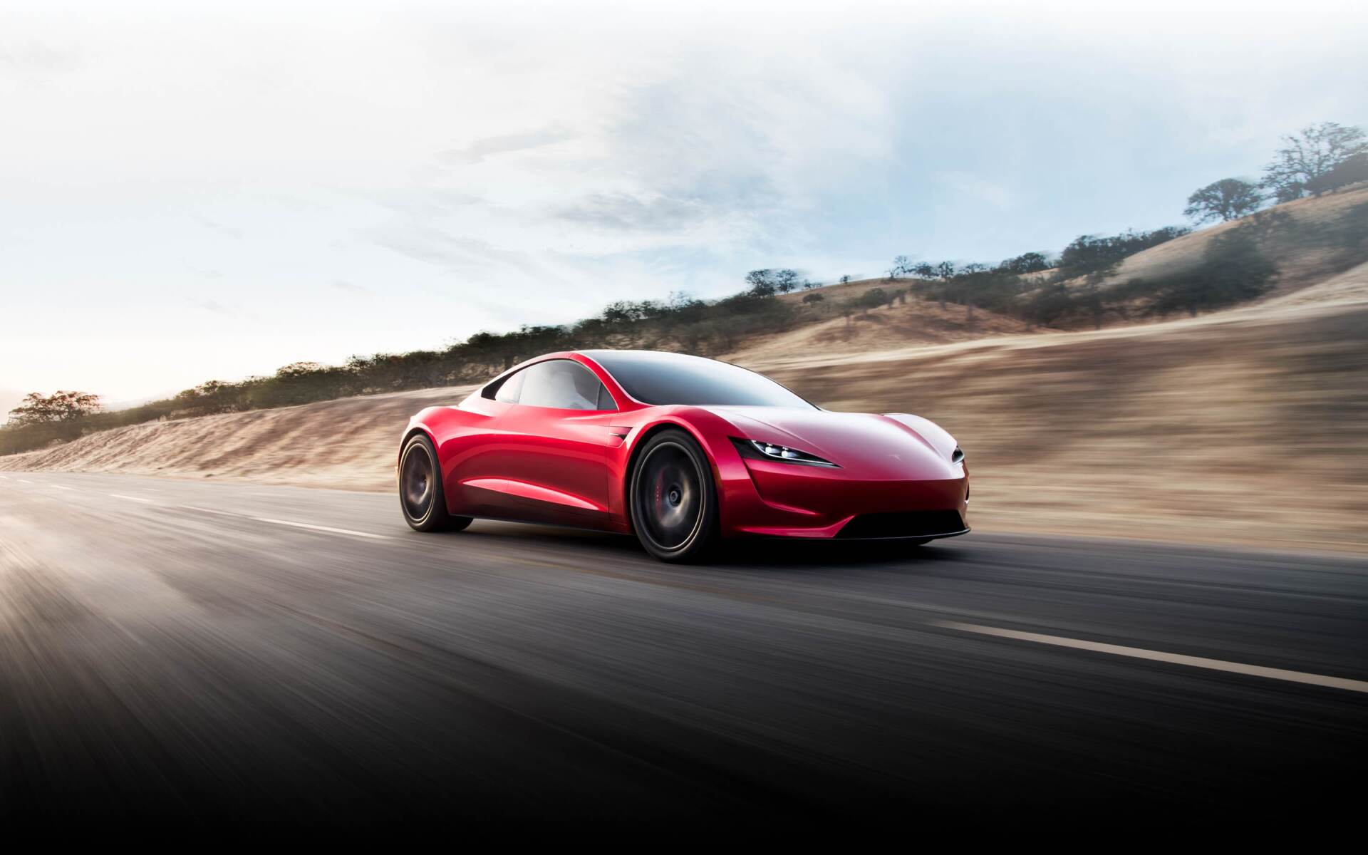 Red sports car driving fast on a winding road with motion blur and dusty hills in the background