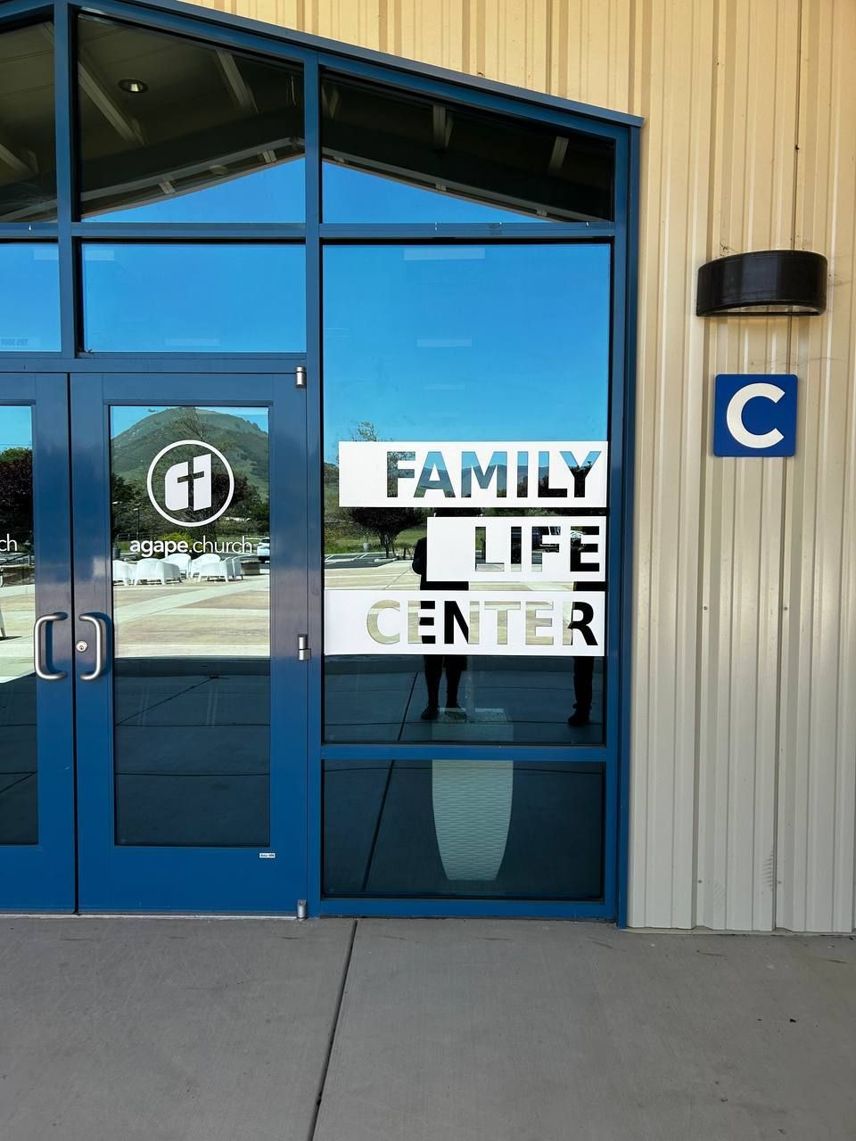 Blue entrance doors of a Family Life Center building with a blue “C” sign beside them.