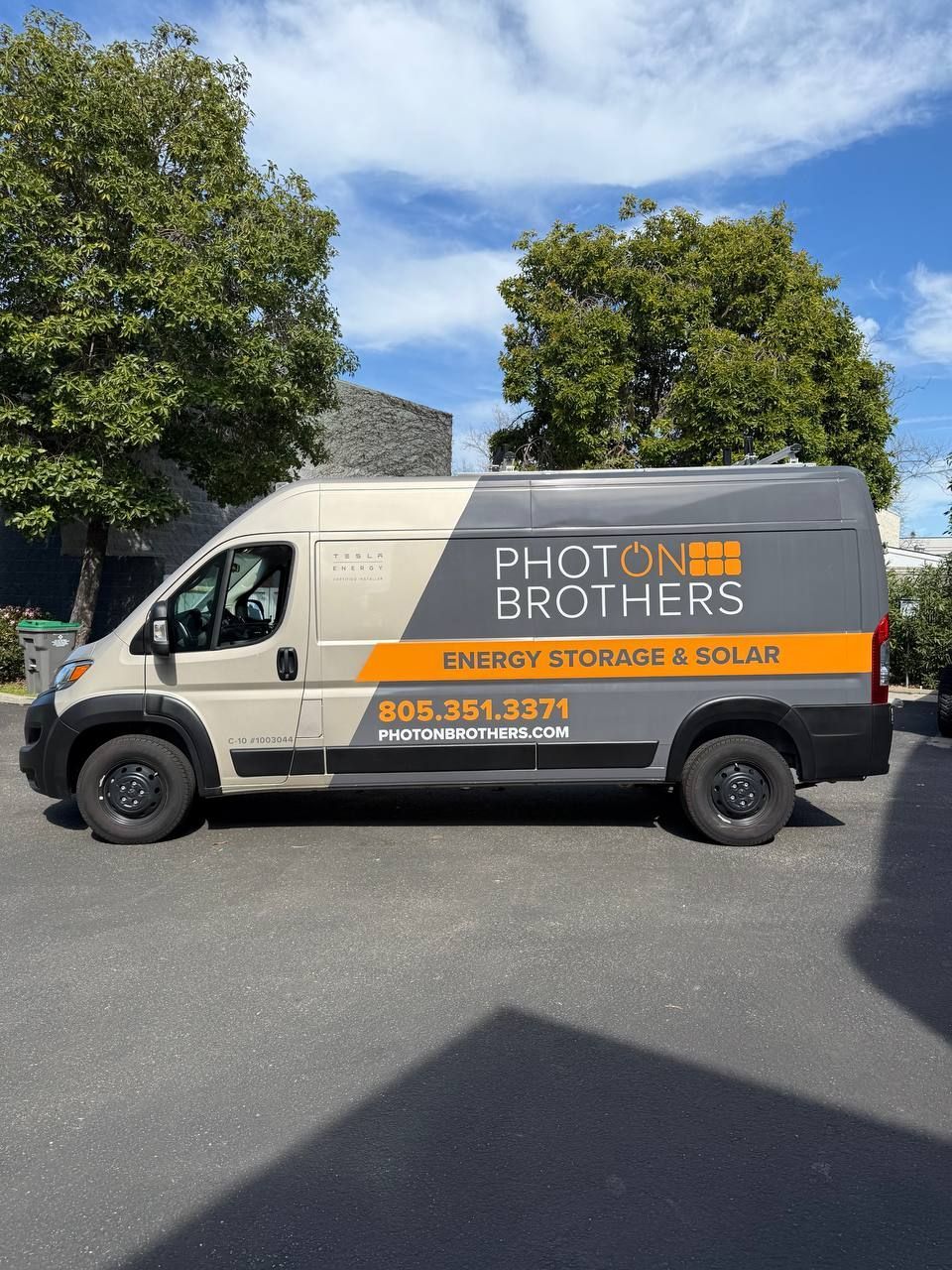 Photon Brothers solar van parked on a street, with orange and gray branding.