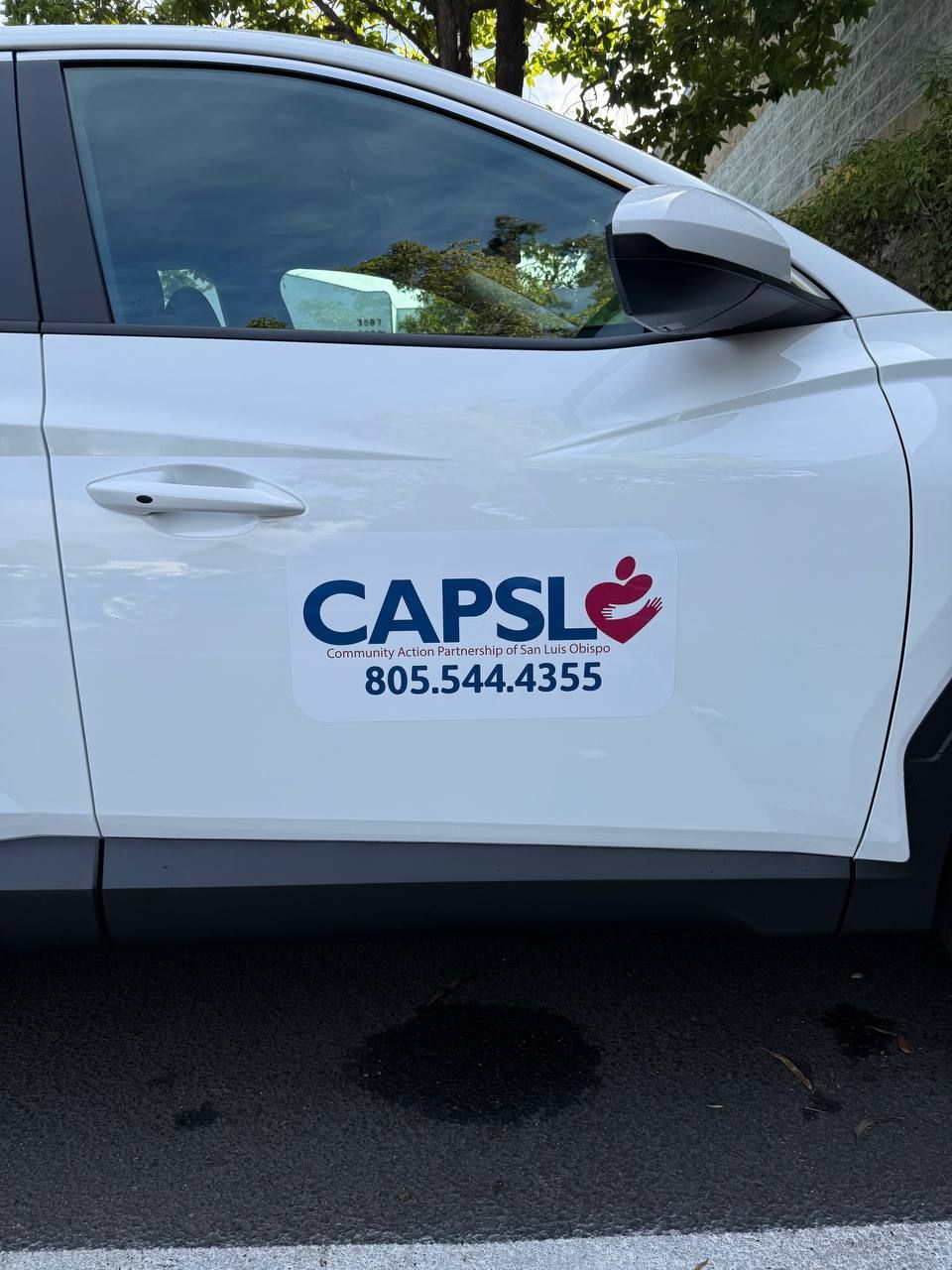 White car door with CAPS logo and phone number 805-544-4355 parked outdoors