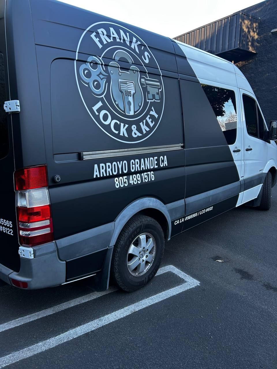 Gray locksmith van with company logo parked in a lot, side view, with “Arroyo Grande, CA” on the panel