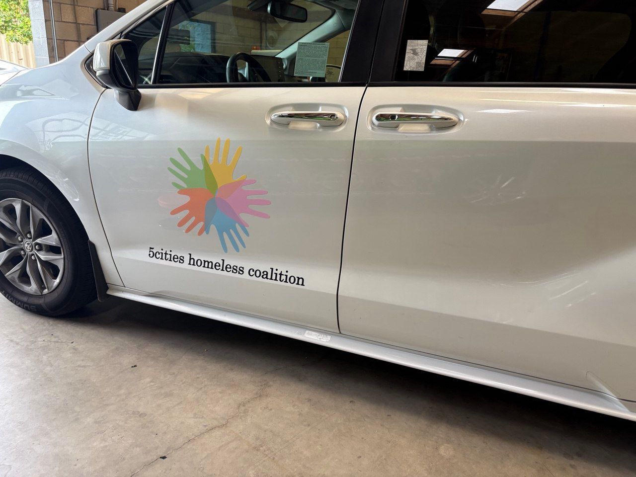 White van with colorful logo and text on the side, parked indoors