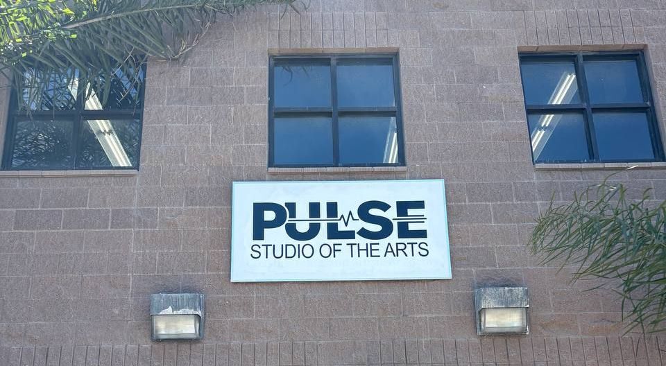 Exterior sign reading “PULSE Studio of the Arts” on a brick building facade.