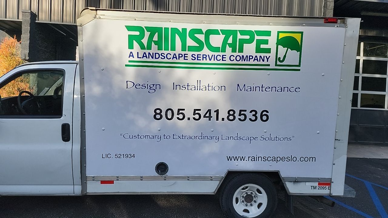 White Rainscape landscaping service truck parked outdoors with company logo and phone number on side