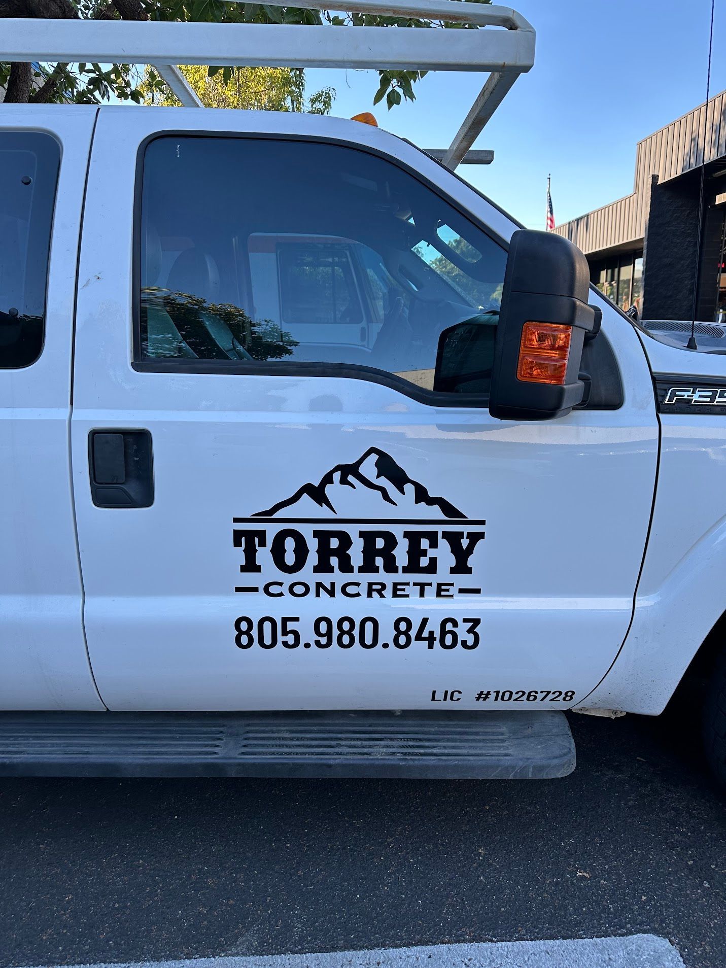 White Torrey Concrete work truck with company logo and phone number on the door.