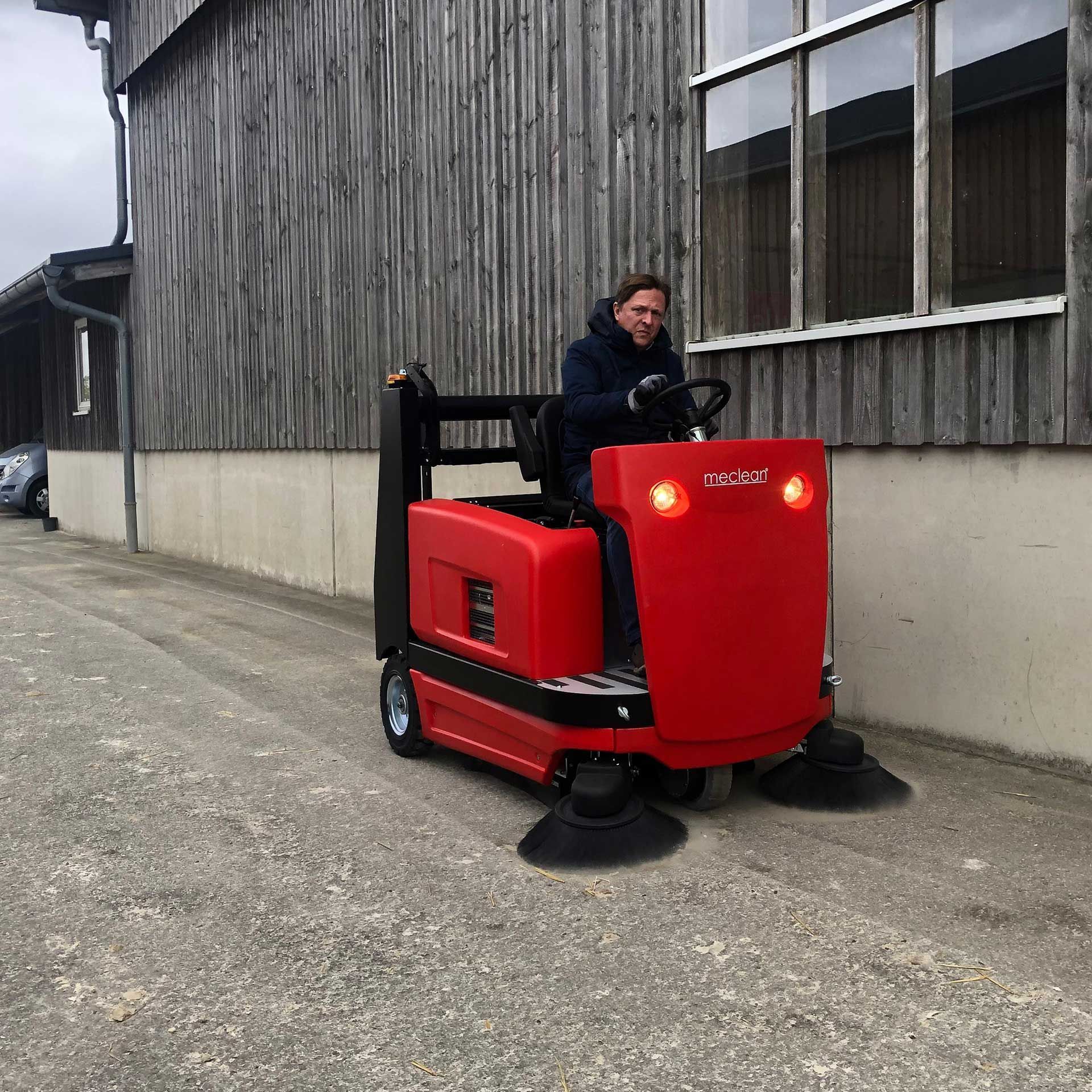 Meclean industriële veegmachine batterij aandrijving BUSTER 1300TTE vegen langs rand gebouw paardenmanege