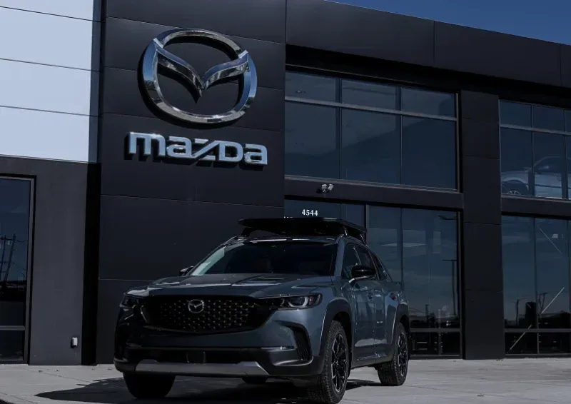 Mazda SUV parked outside a Mazda dealership under a clear sky