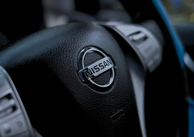 Close-up of a Nissan steering wheel with the logo centered in a dark car interior