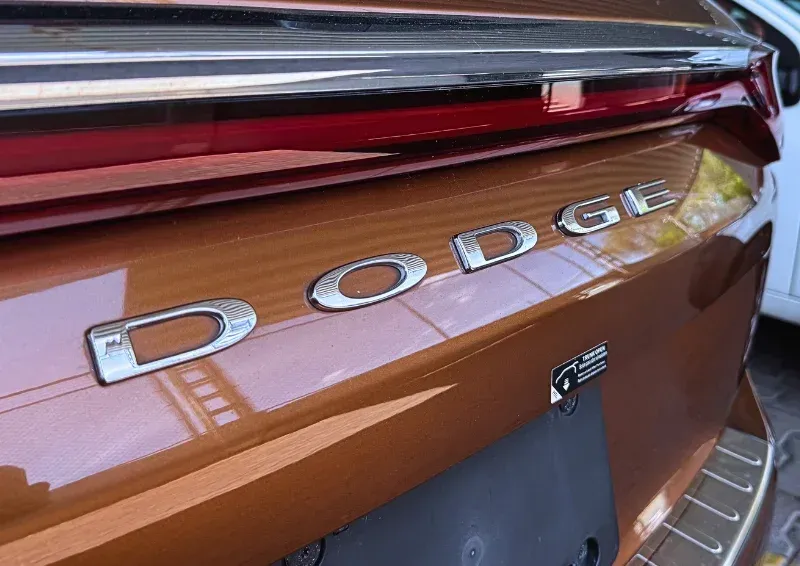 Close-up of a brown Dodge vehicle trunk with chrome lettering and rear taillight.