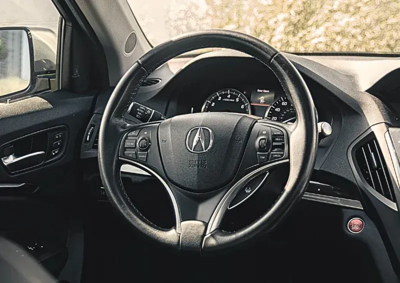 Interior of a Honda car, showing the steering wheel, dashboard, and front driver’s seat area.