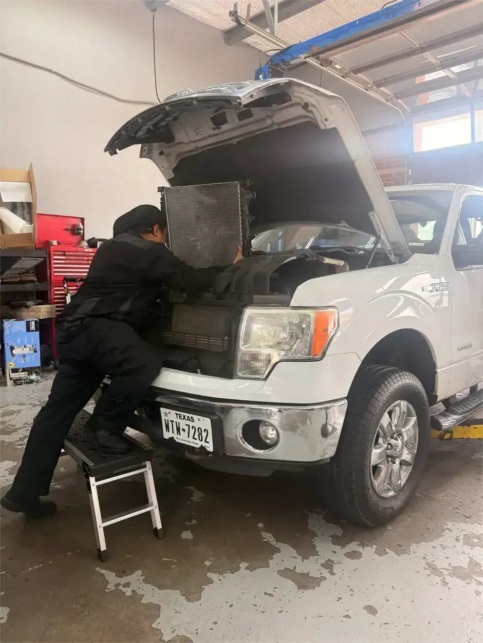Worker in gloves holding a car radiator in a workshop