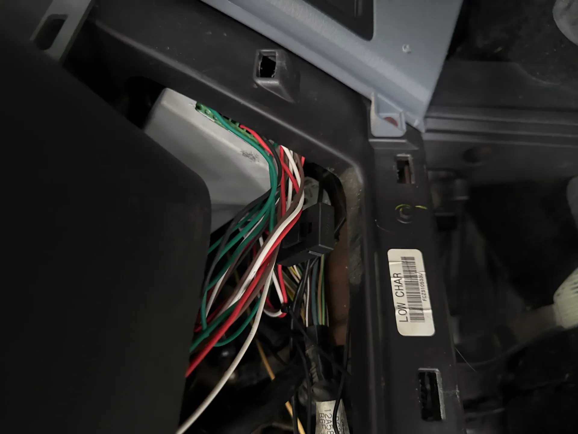 Exposed multicolored wires and cable harness inside a car dashboard panel