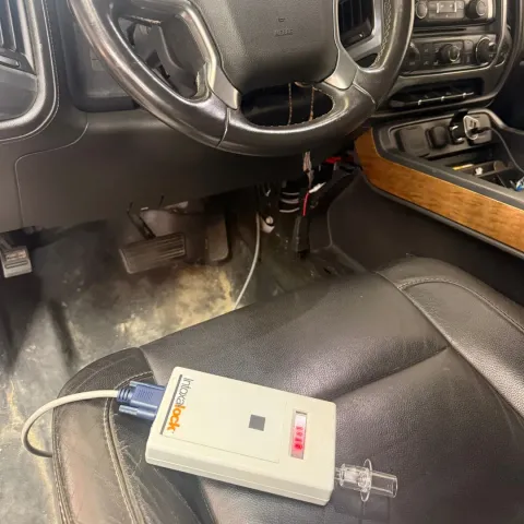 Car interior with a small electronic device and clear tube resting on the passenger seat near the center console
