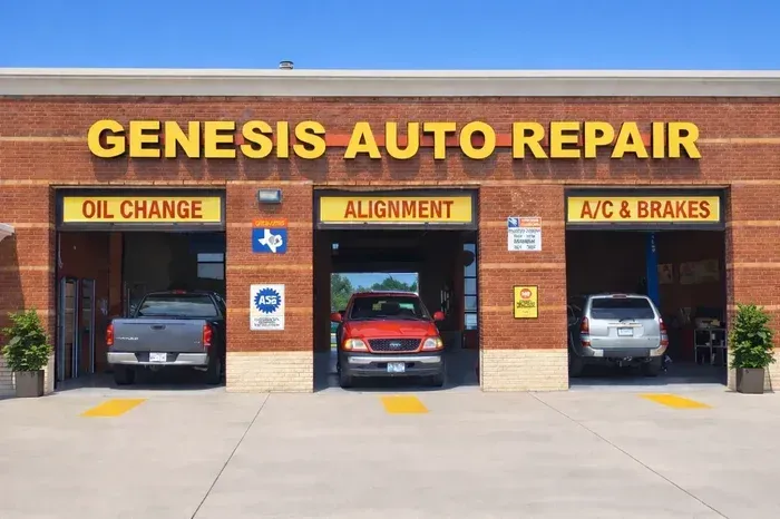 Genesis Auto Repair storefront with three service bays labeled oil change, alignment, and A/C & brakes, cars inside