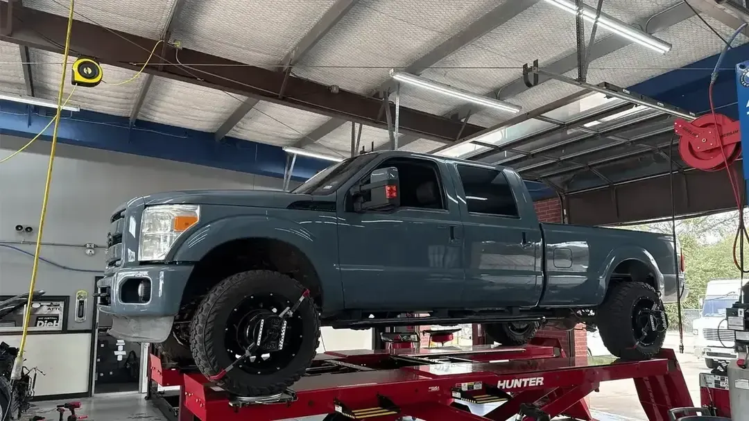 Auto repair shop with cars on lifts and a red alignment machine in the center.