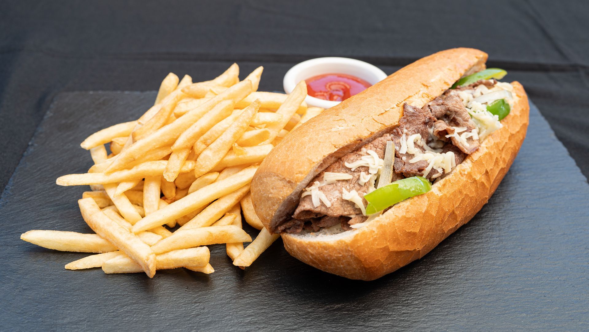Sandwich with fries and ketchup on a dark tray