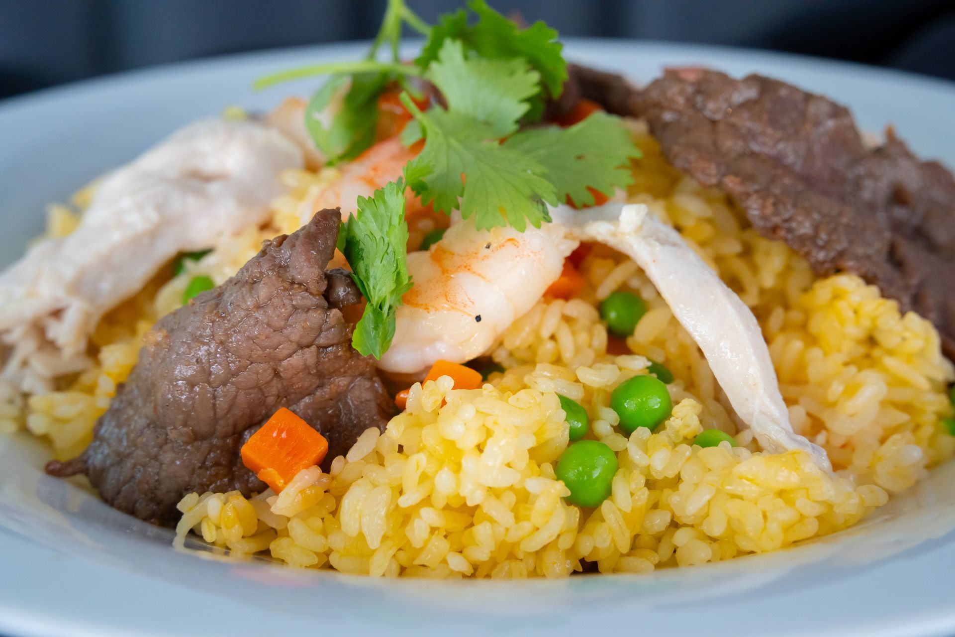 Plated yellow rice with beef, shrimp, vegetables, and cilantro garnish