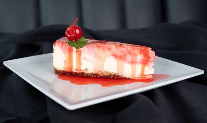 Thin slices of raw red meat on a white plate, arranged in overlapping layers