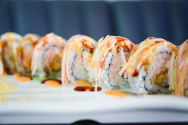 Sushi rolls topped with sauce arranged on a white plate