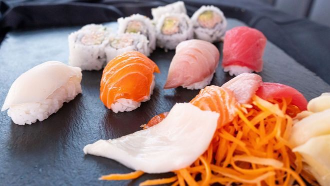 Sushi assortment on a black plate with chopsticks and soy sauce