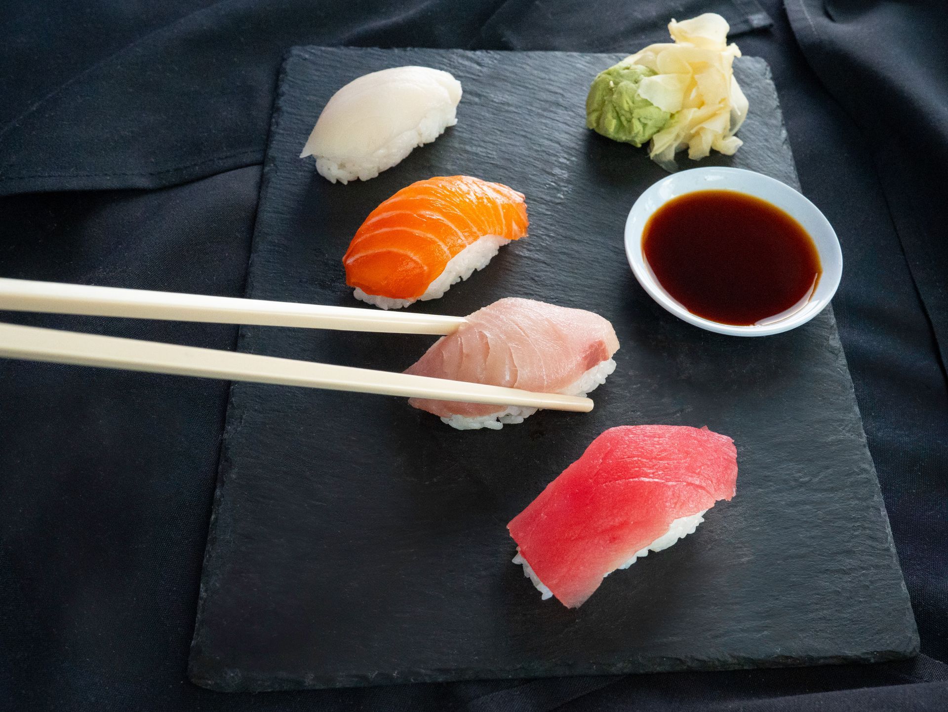 Sushi assortment with chopsticks and soy sauce on a black plate
