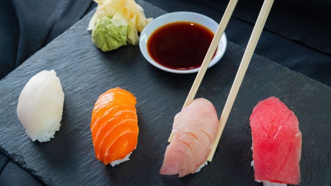 Sushi assortment on a black plate with chopsticks and soy sauce