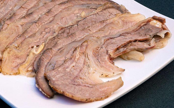 Thin slices of raw red meat on a white plate, arranged in overlapping layers