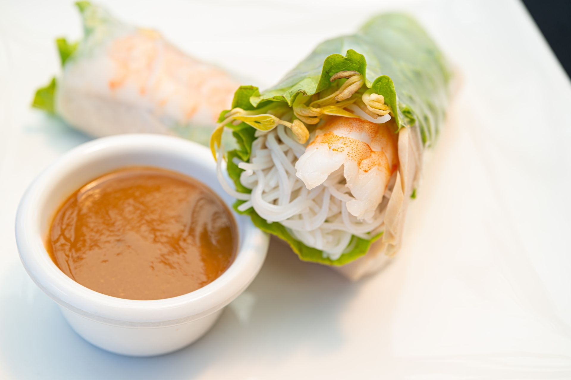 Fresh spring rolls with orange dipping sauce on a white plate